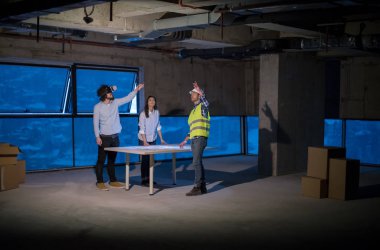 Gruptaki genç iş adamları, inşaat sahasındaki mimar ve mühendis yeni açılan ofiste dizüstü bilgisayar kullanarak belge ve iş akışını kontrol ediyorlar.