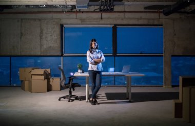 İnşaat alanında genç bayan mimarın portresi yeni açılan ofiste dizüstü bilgisayarla belge ve iş akışını kontrol ediyor