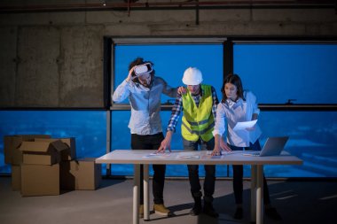 Gruptaki genç iş adamları, inşaat sahasındaki mimar ve mühendis yeni açılan ofiste dizüstü bilgisayar kullanarak belge ve iş akışını kontrol ediyorlar.