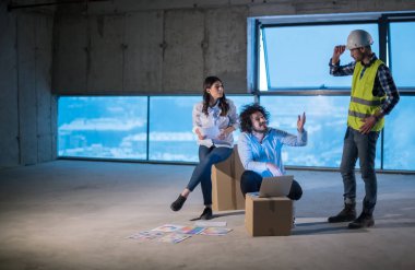 Gruptaki genç iş adamları, inşaat sahasındaki mimar ve mühendis yeni açılan ofiste dizüstü bilgisayar kullanarak belge ve iş akışını kontrol ediyorlar.