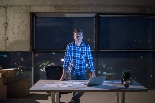 建設現場の若い男性エンジニアの肖像夜に新しいスタートアップオフィスでノートパソコンを使用して文書やビジネスワークフローをチェック — ストック写真