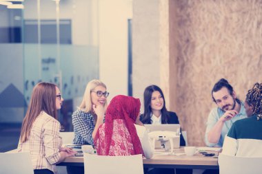 Yeni iş planlarını tartışan, laptop ve tablet bilgisayarlar üzerinde çalışan çok ırklı bir girişim ekibi yeni iş geliştirme teknolojileri hakkında bilgi toplarken,