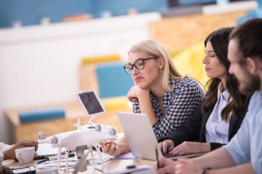 Yeni iş planlarını tartışan, laptop ve tablet bilgisayarlar üzerinde çalışan çok ırklı bir girişim ekibi yeni iş geliştirme teknolojileri hakkında bilgi toplarken,