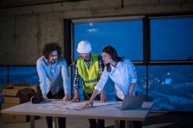 Gruptaki genç iş adamları, inşaat sahasındaki mimar ve mühendis yeni açılan ofiste dizüstü bilgisayar kullanarak belge ve iş akışını kontrol ediyorlar.