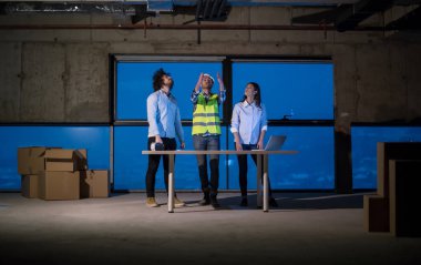 Gruptaki genç iş adamları, inşaat sahasındaki mimar ve mühendis yeni açılan ofiste dizüstü bilgisayar kullanarak belge ve iş akışını kontrol ediyorlar.