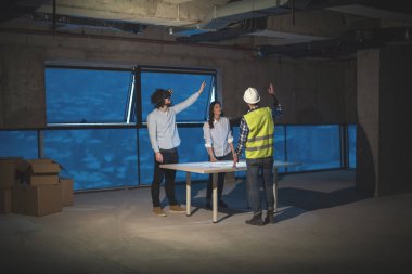 Gruptaki genç iş adamları, inşaat sahasındaki mimar ve mühendis yeni açılan ofiste dizüstü bilgisayar kullanarak belge ve iş akışını kontrol ediyorlar.