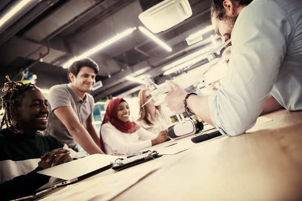 Yeni iş planlarını tartışan, laptop ve tablet bilgisayarlar üzerinde çalışan çok ırklı bir girişim ekibi yeni iş geliştirme teknolojileri hakkında bilgi toplarken,