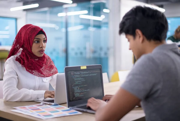 successful black muslim business woman having a meeting with her indian male colleague working on the laptop at modern startup office