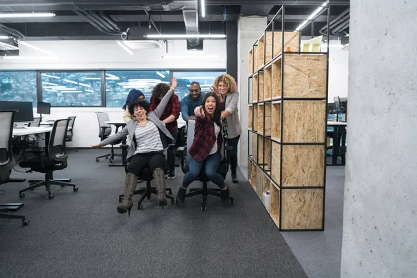 Multiethnisches Geschäftsteam rast auf Bürostühlen — Stockfoto