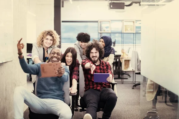 Team aziendale multietnico che corre su sedie da ufficio — Foto Stock