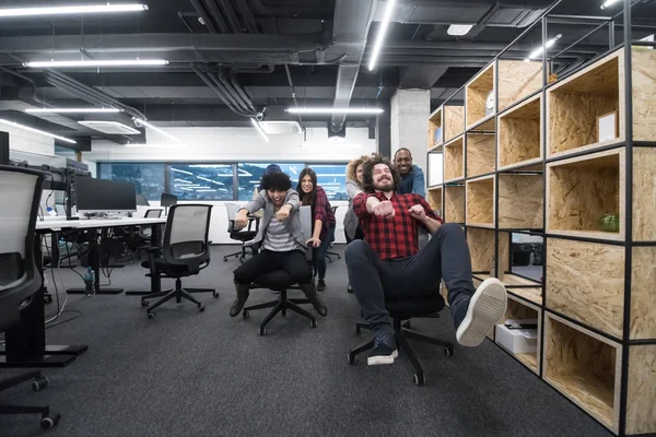 Többnemzetiségű üzleti csapat versenyzés irodai székeken — Stock Fotó