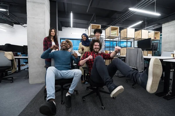 사무실 의자 위에서 레이스를 벌이고 있는 다 민족 사업 팀 — 스톡 사진