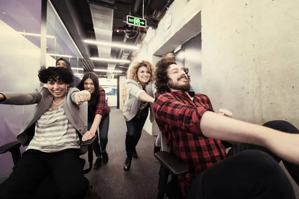 Equipe de negócios multiétnica competindo em cadeiras de escritório — Fotografia de Stock
