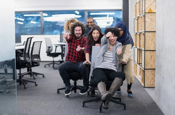 Multi-etnische business team racen op bureaustoelen — Stockfoto