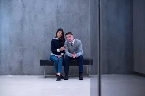 Obchodní pár pomocí mobilního telefonu při sezení na lavičce — Stock fotografie