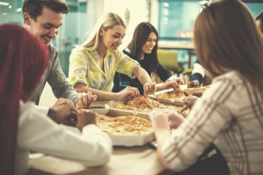 Çok ırklı iş adamları pizza yiyor.