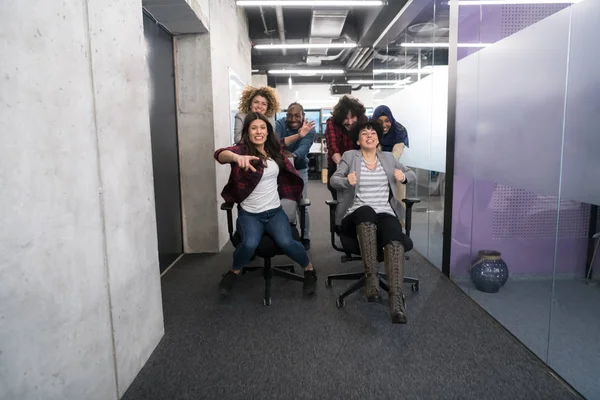 Többnemzetiségű üzleti csapat versenyzés irodai székeken — Stock Fotó