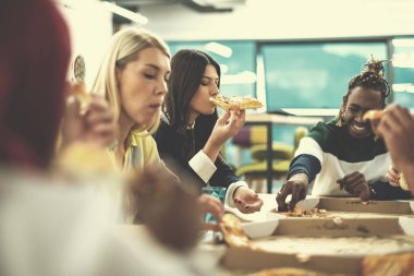 Çok ırklı iş adamları pizza yiyor.