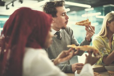 Çok ırklı iş adamları pizza yiyor.