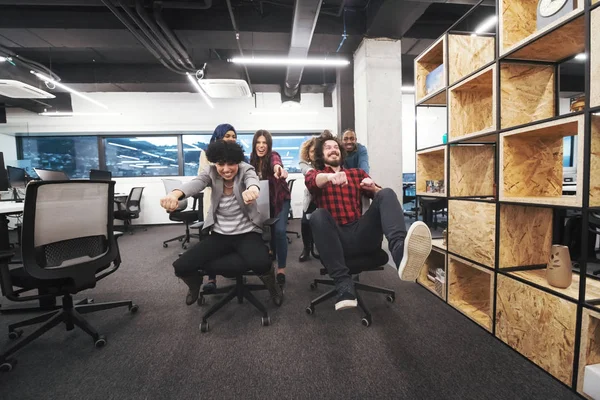 Multiethnisches Geschäftsteam rast auf Bürostühlen — Stockfoto