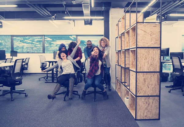 Equipe de negócios multiétnica competindo em cadeiras de escritório — Fotografia de Stock