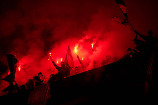 футбольные хулиганы с маской, держащие факелы в огне
