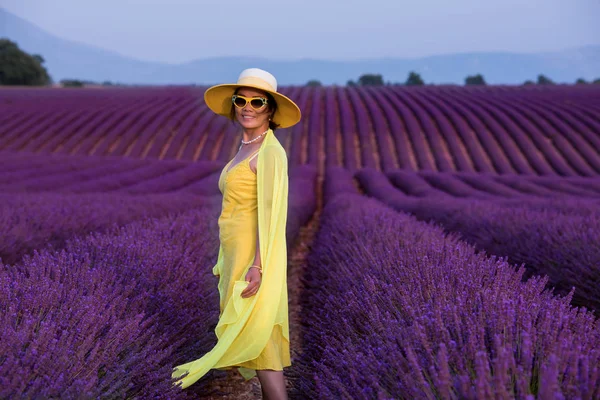 Asiatisk kvinna i gul klänning och hatt på lavendelfält — Stockfoto