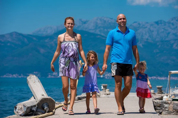 Jeune famille heureuse marchant au bord de la mer — Photo