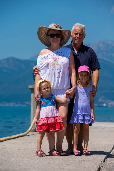 Portret van grootouders en kleindochters staande door de zee — Stockfoto