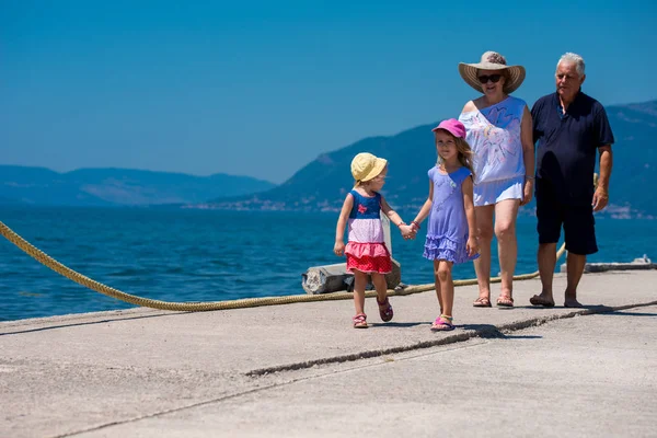 Grands-parents et petites-filles marchant au bord de la mer — Photo