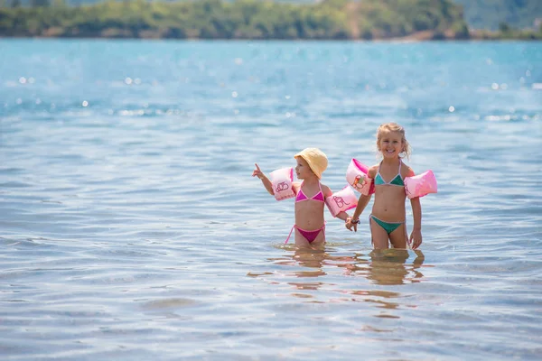 Kleine meisjes met zwemmen armbandjes spelen in ondiep water — Stockfoto