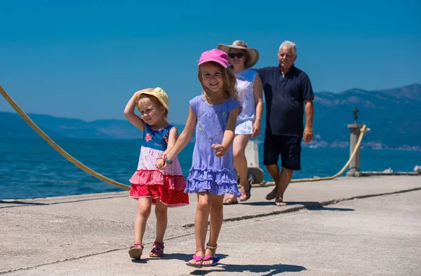 Grands-parents et petites-filles marchant au bord de la mer — Photo