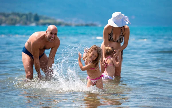 Ευτυχισμένη οικογένεια που πιτσιλίζει ο ένας τον άλλο στην παραλία — Φωτογραφία Αρχείου