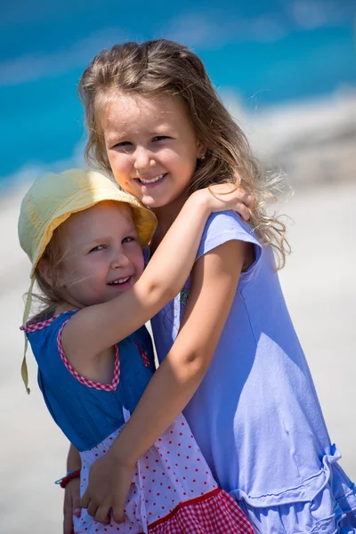 Hermanas pequeñas abrazándose en la costa de la playa — Foto de Stock