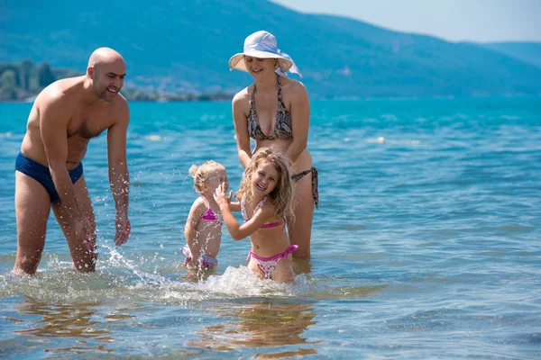 Gelukkige familie spetteren elkaar op het strand — Stockfoto