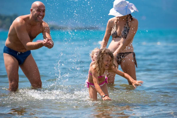 Heureux famille éclaboussant mutuellement à la plage — Photo