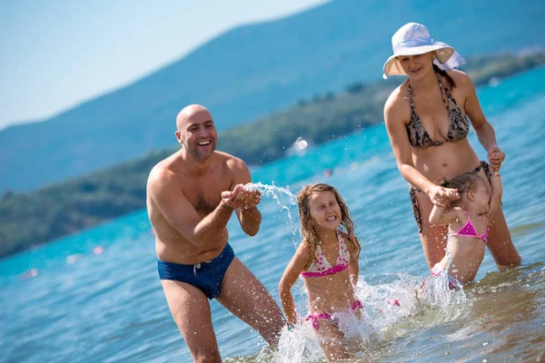 Família feliz salpicando uns aos outros na praia — Fotografia de Stock