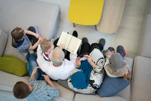 Верхний вид современных мусульманских бабушки и дедушки с внуками читать в — стоковое фото