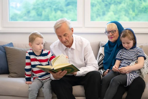 Modern muslim grandparents with grandchildren reading Quran — Stock Photo, Image