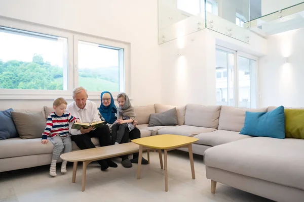 Modern muslim grandparents with grandchildren reading Quran — Stock Photo, Image