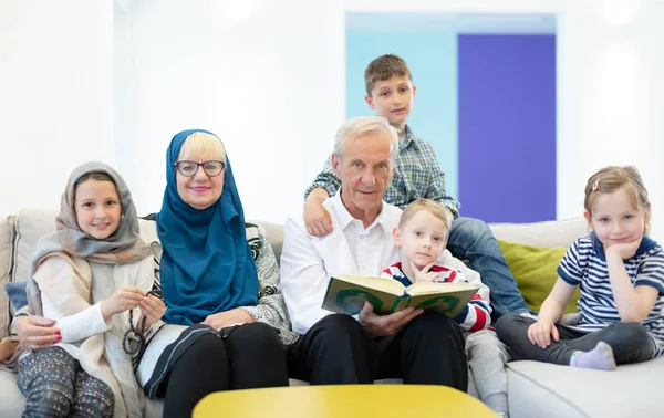 Modern muslim grandparents with grandchildren reading Quran — Stock Photo, Image