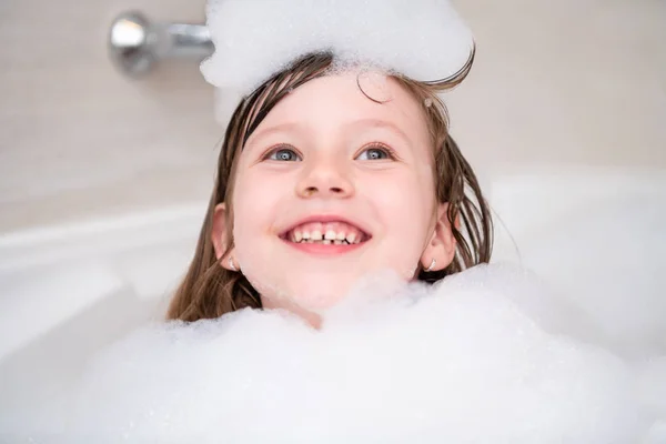 Kleines Mädchen in der Badewanne spielt mit Schaum — Stockfoto