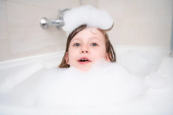 Kleines Mädchen in der Badewanne spielt mit Schaum — Stockfoto