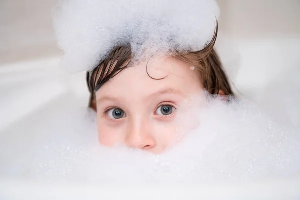 Liten flicka i badet leker med skum — Stockfoto