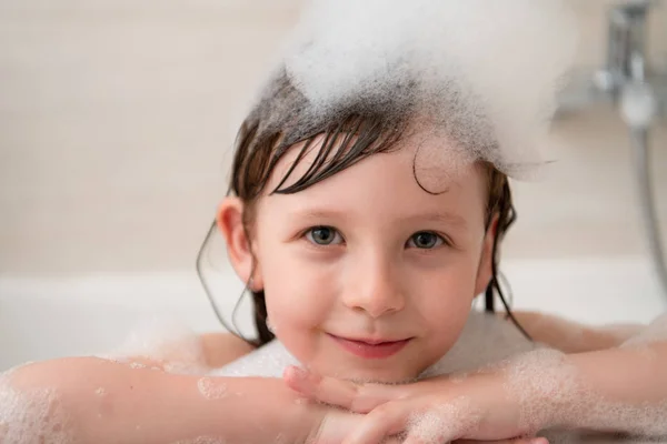 Kleines Mädchen in der Badewanne spielt mit Schaum — Stockfoto