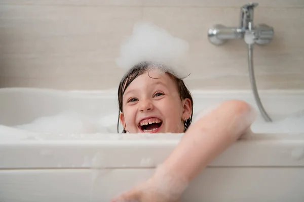 Kleines Mädchen in der Badewanne spielt mit Schaum — Stockfoto