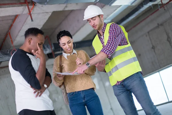 Architect showing house design plans to a young multiethnic coup — Stock Photo, Image