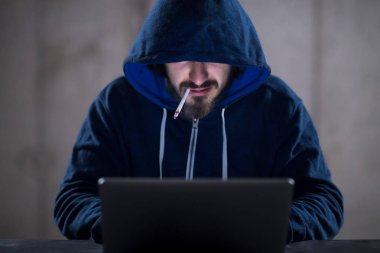 karanlık ofiste çalışırken dizüstü bilgisayar kullanarak genç hacker