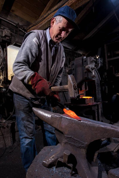 blacksmith manually forging the molten metal
