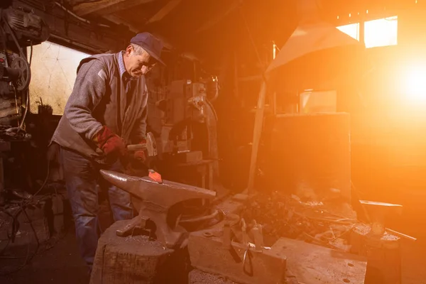 Herrero forja manualmente el metal fundido con luz solar throu —  Fotos de Stock